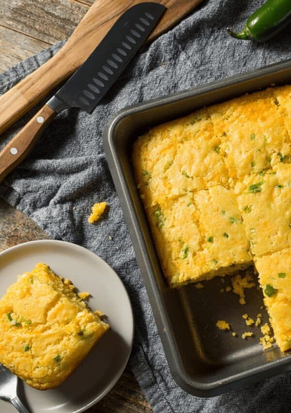 A pan of Mexican Cornbread with a plate of cornbread next to it