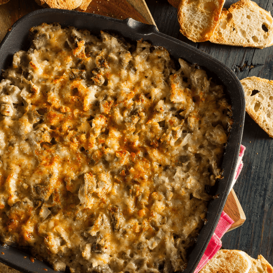 Artichoke Dip in a skillet with bread for dipping