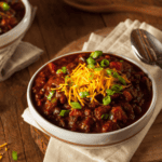 Two bowls of crockpot chili on a wooden table - 9
