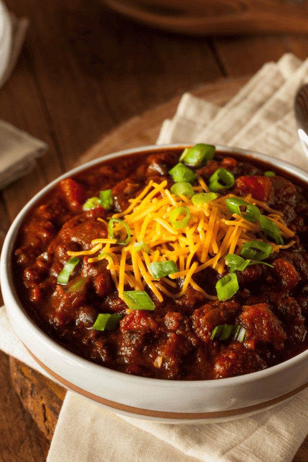 Two bowls of crockpot chili on a wooden table