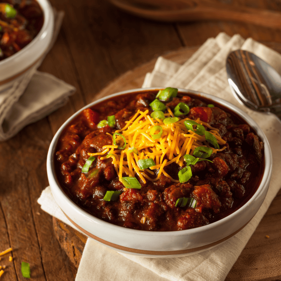Two bowls of crockpot chili on a wooden table