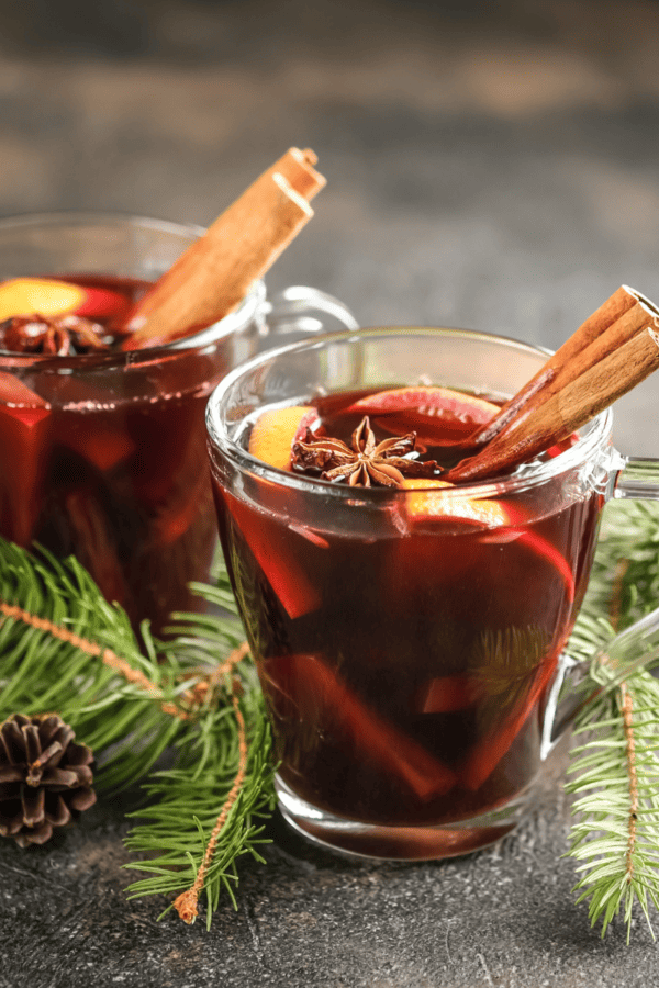 Two mugs of Christmas Punch surrounded by evergreen branches