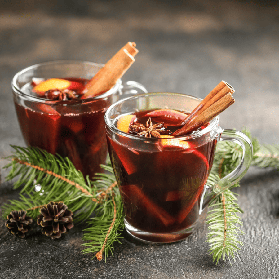 Two mugs of Christmas Punch surrounded by evergreen branches