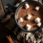 Close up image of crockpot hot chocolate in a blue mug with marshmallows