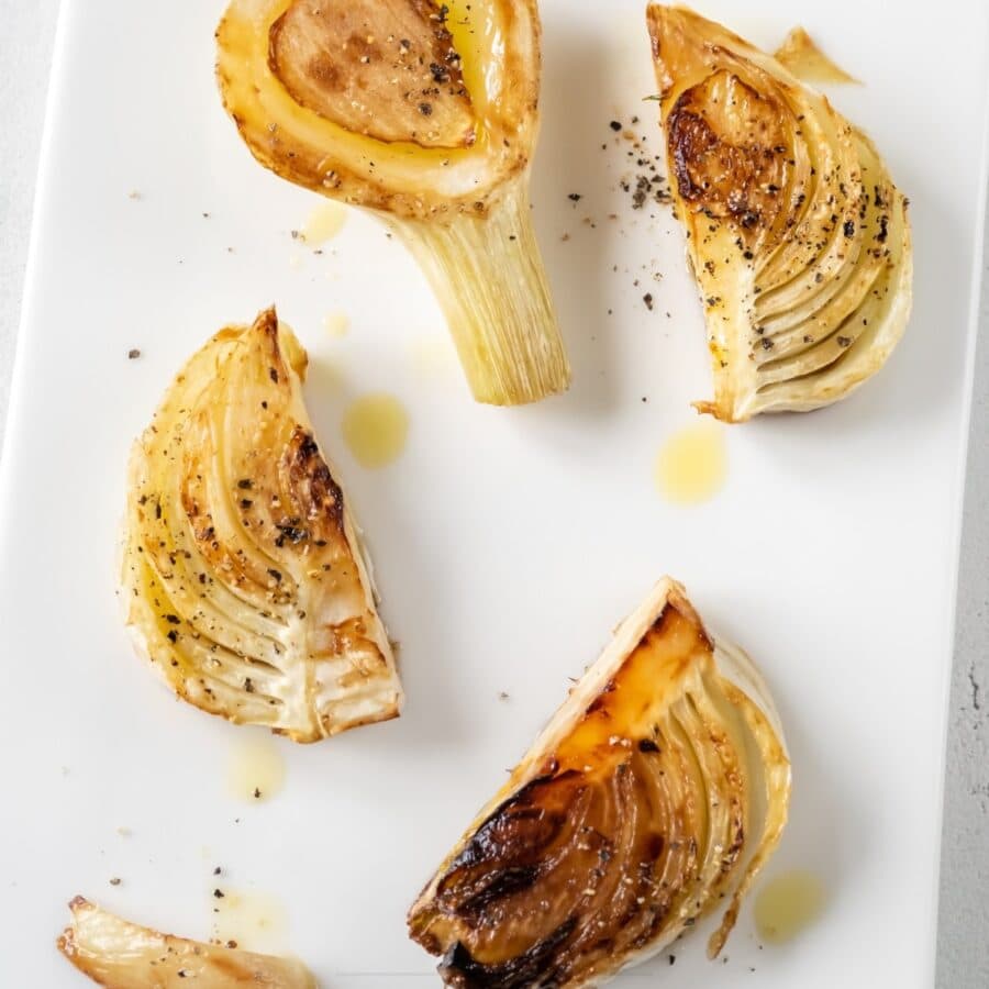 Overhead image of roasted fennel on a white serving tray