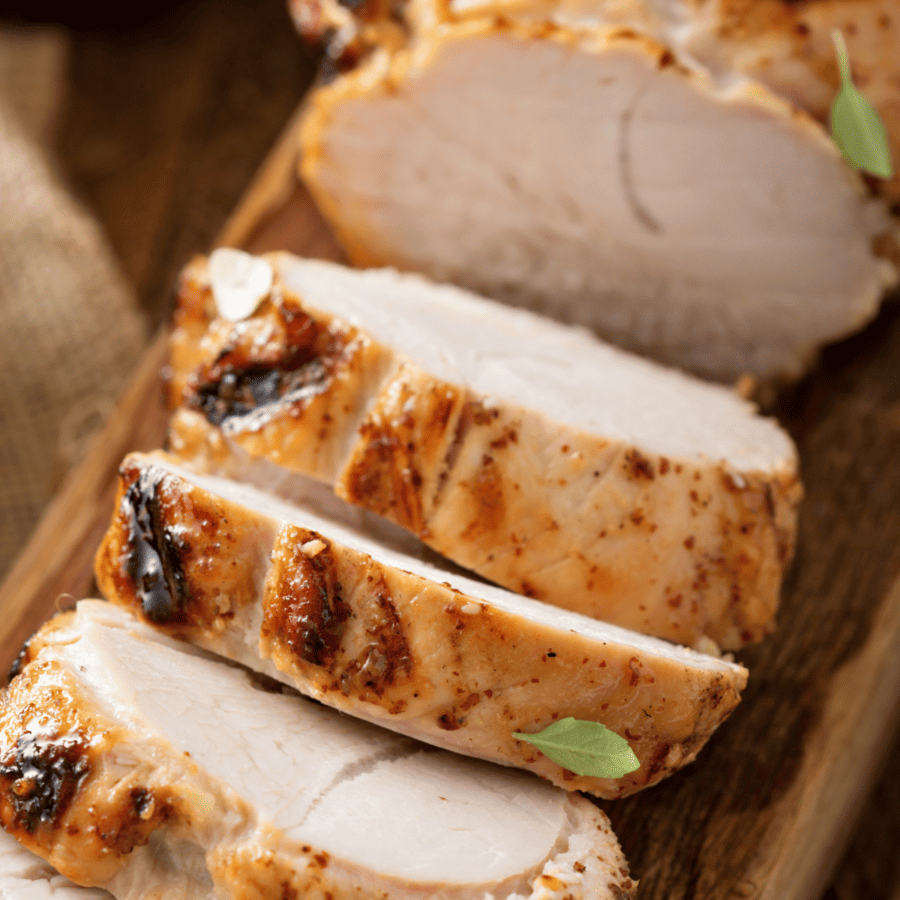 Close up image of roasted turkey breast sliced on a wooden cutting board