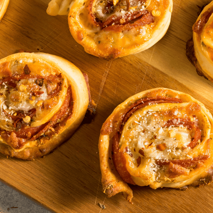 close up image of pizza pinwheels on a wooden cutting board