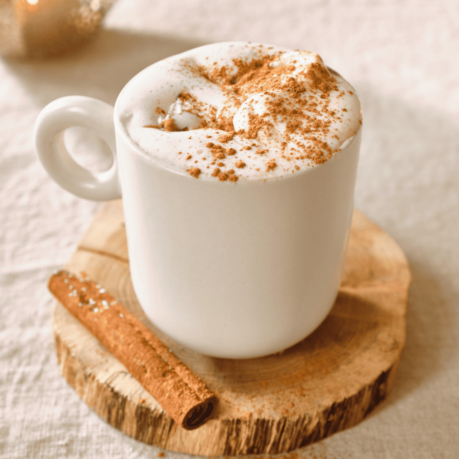 a white mug of white chocolate hot chocolate sitting on a piece of wood