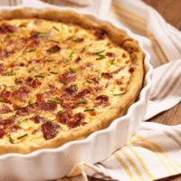 Breakfast Quiche in a white pie dish on top of a dish towel