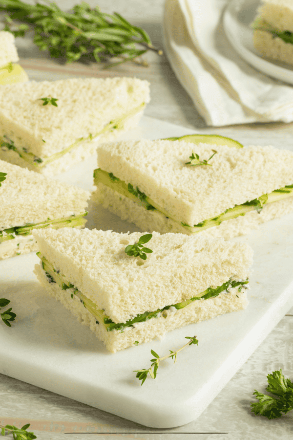 Cucumber Sandwiches cut into triangles on a white cutting board