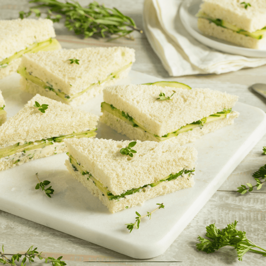 Cucumber Sandwiches cut into triangles on a white cutting board