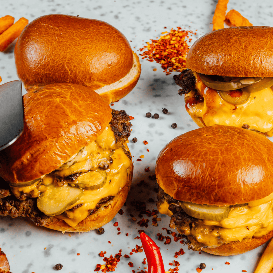 multiple smash burgers on a white background with pepper flakes scattered
