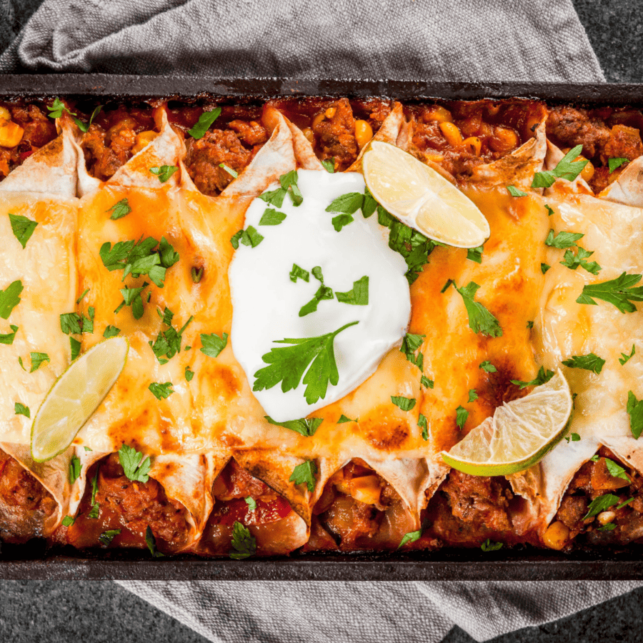 Vegetarian Enchiladas in a rectangular baking dish garnished with sour cream and lime