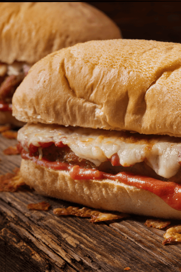 Two Chicken Parm Sandwiches on a wooden cutting board