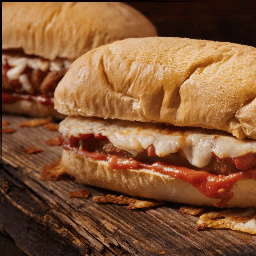 Two Chicken Parm Sandwiches on a wooden cutting board