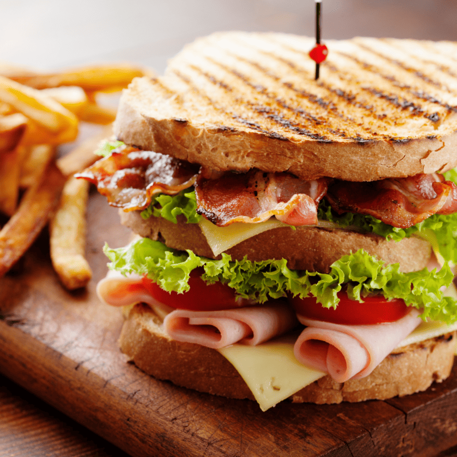 Club Sandwich on a wooden cutting board with French fries