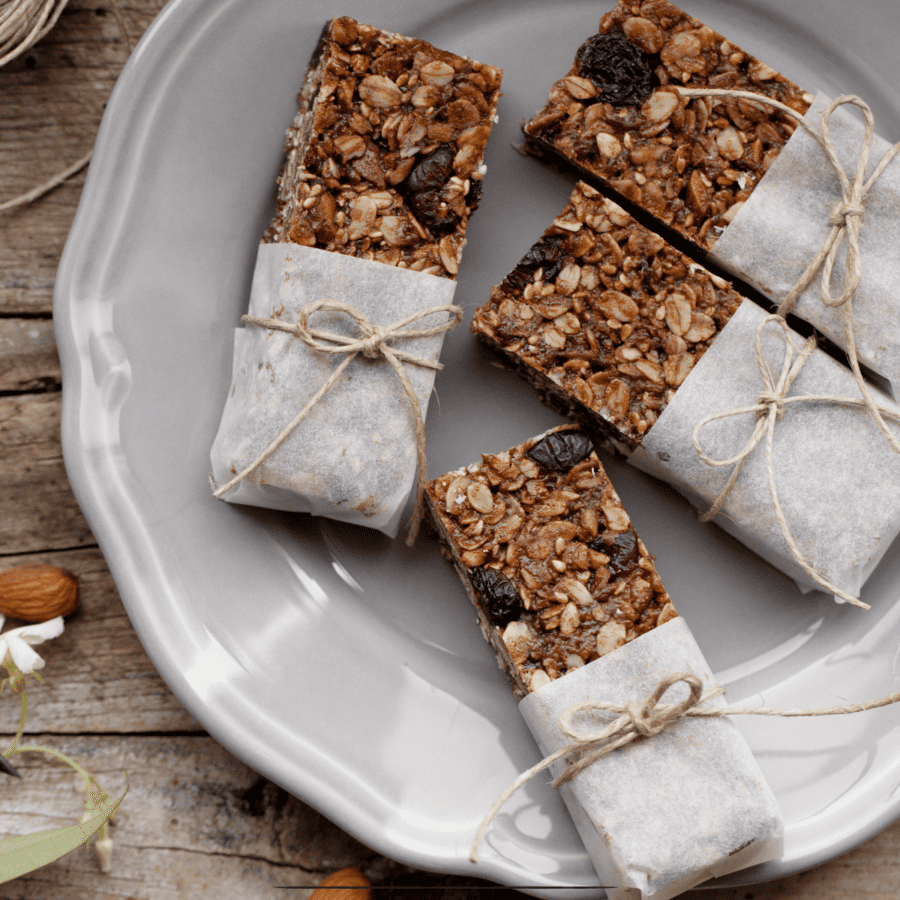 Overhead shot of homemade granola bars wrapped in parchment paper on a plate