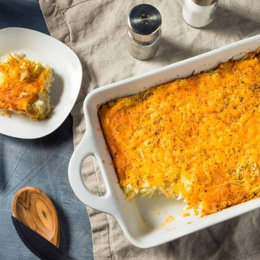 Overhead image of hashbrown casserole in a baking dish with a plate next to it