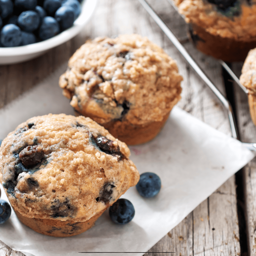 Close up image of lemon blueberry muffins on parchment paper sitting on a wooden table top