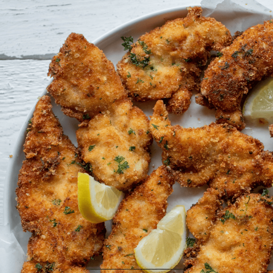 Close up image of parmesan crusted chicken breasts with lemon garnish