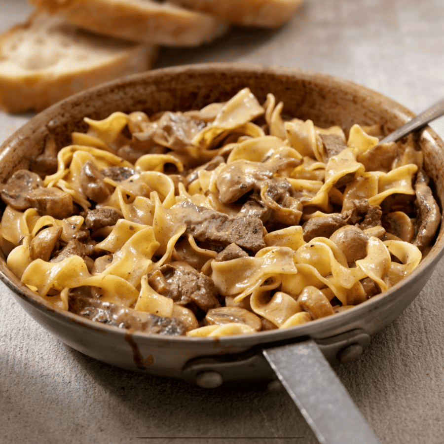 Slow Cooker Beef Stroganoff in a skillet with slices of bread behind it