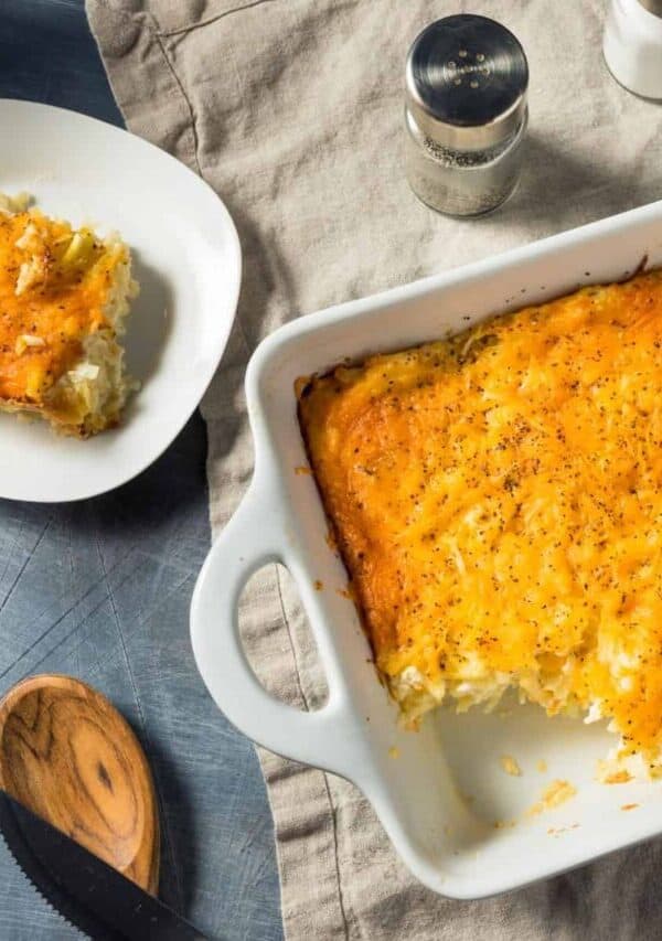 Overhead image of hashbrown casserole in a baking dish with a plate next to it
