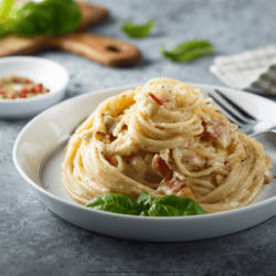 A swirled portion of Bacon Pasta on a white high-rimmed plate