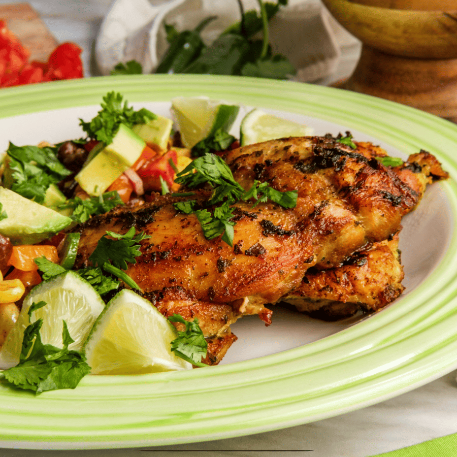 Cilantro Lime Chicken on a green and white plate with chopped lime and corn salsa