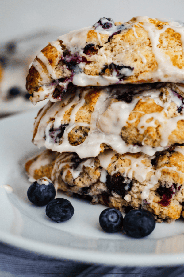 Three lemon blueberry scones stacked on a white plate