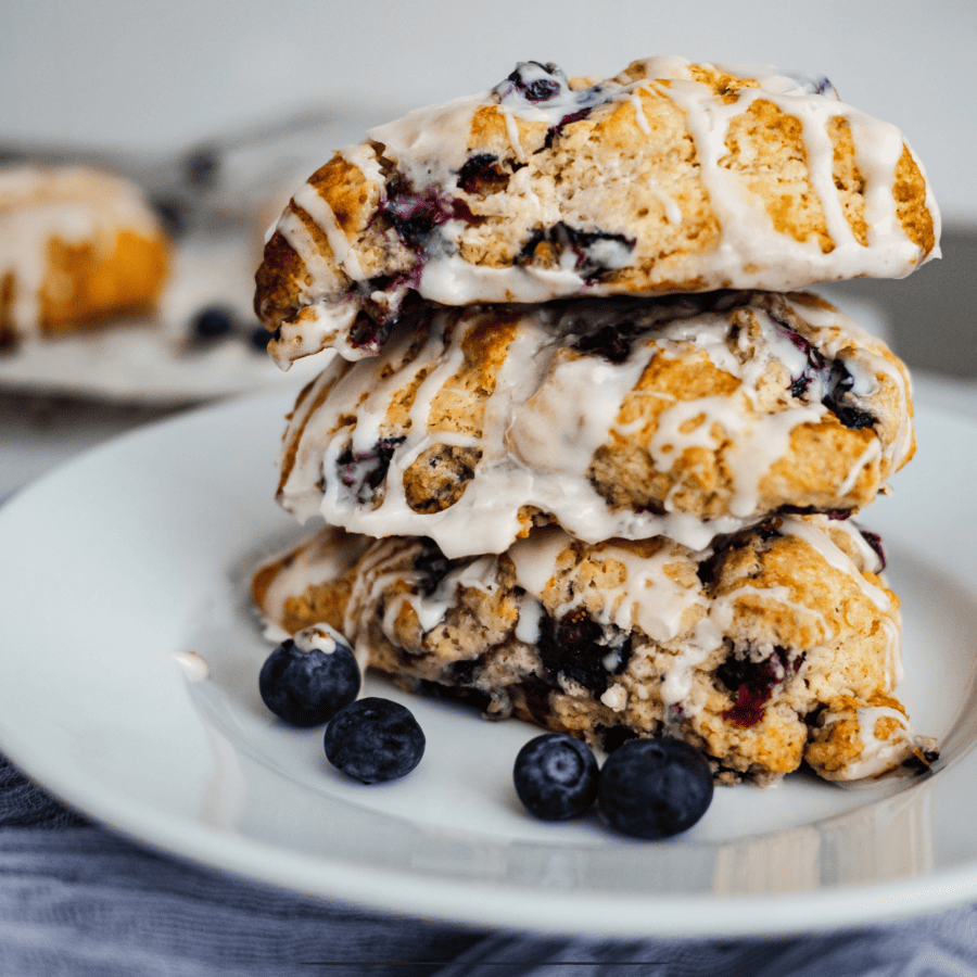 Three lemon blueberry scones stacked on a white plate