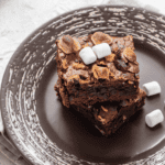 Close up image of S'mores Brownies on a plate with loose marshmallows