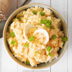 Overhead shot of Southern Potato Salad in a white bowl garnished with hard boiled egg and green onion