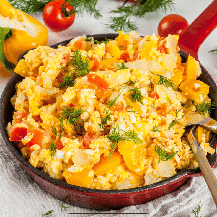 Close up image of a Breakfast Skillet in a red skillet being served with a wooden spoon