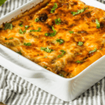 Chicken lasagna in a white baking dish on a striped cloth