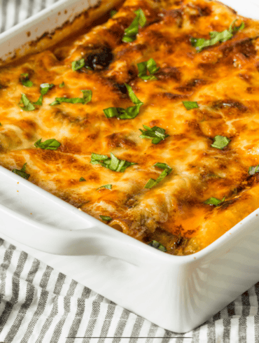 Chicken lasagna in a white baking dish on a striped cloth