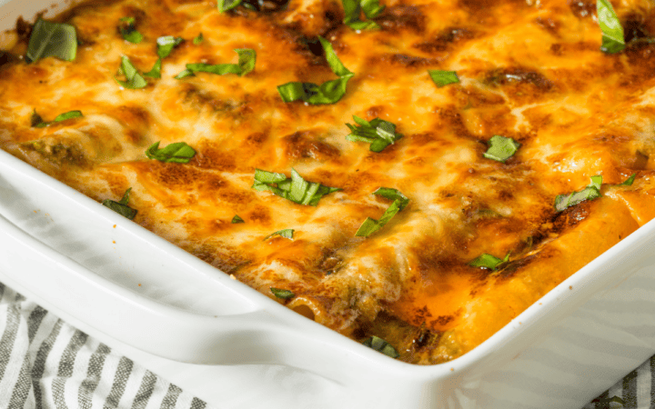 Chicken lasagna in a white baking dish on a striped cloth