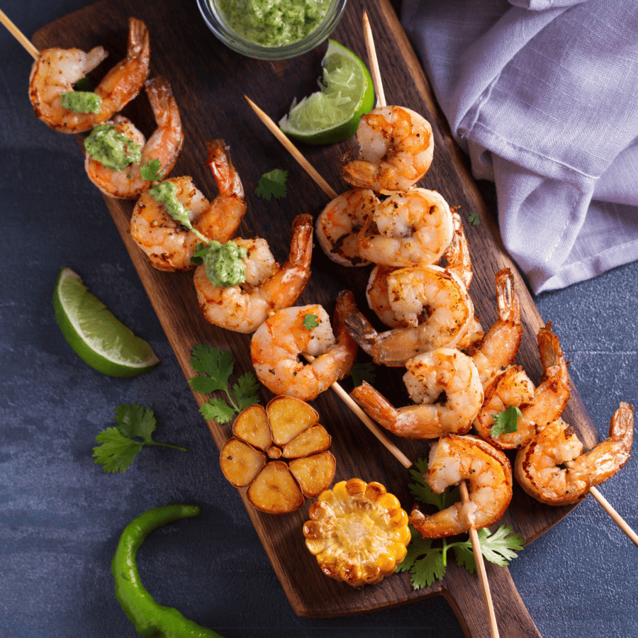 Cilantro Lime Shrimp on skewers laying on a wooden cutting board