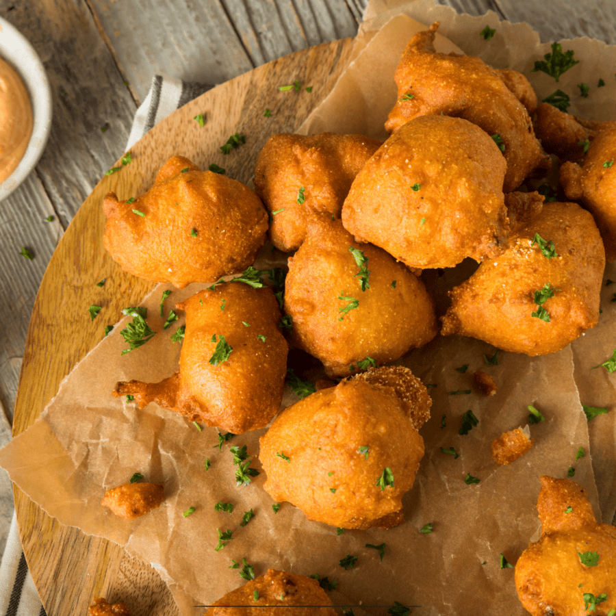 Overhead image of hush puppies on parchment paper with dipping sauce