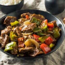 Pepper Steak in a stone colored bowl with a bowl of rice next to it