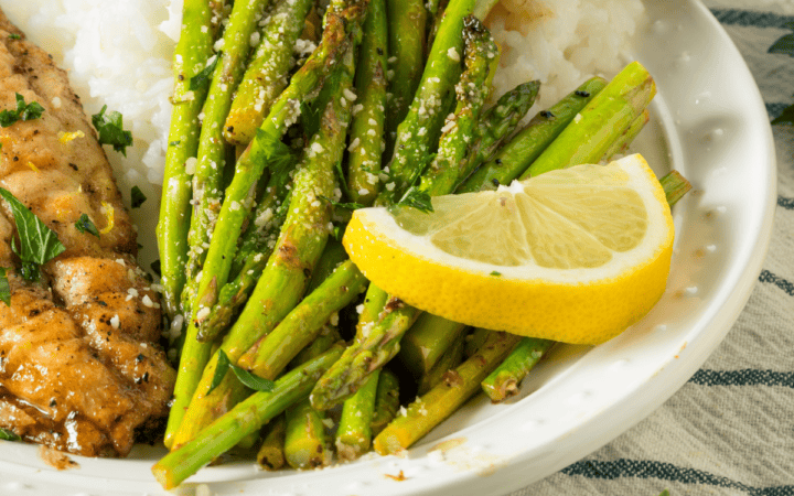 Close up image of sauteed asparagus on a white plate