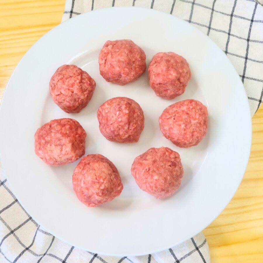 Eight balls of ground beef on a white plate