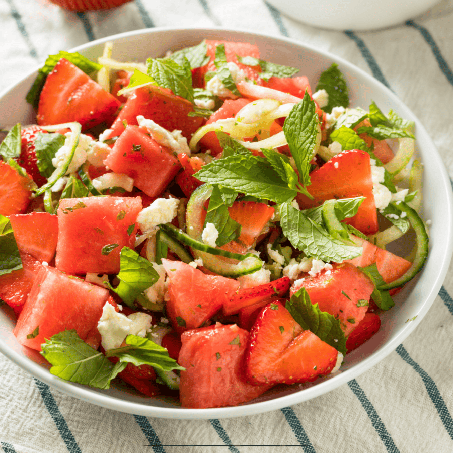 Overhead image of Watermelon Feta Salad in a white bowl on a striped cloth