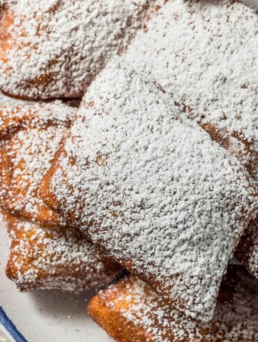 Overhead image of beignets dusted with powdered sugar on a plate
