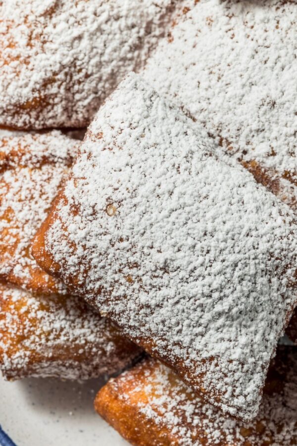 Overhead image of beignets dusted with powdered sugar on a plate