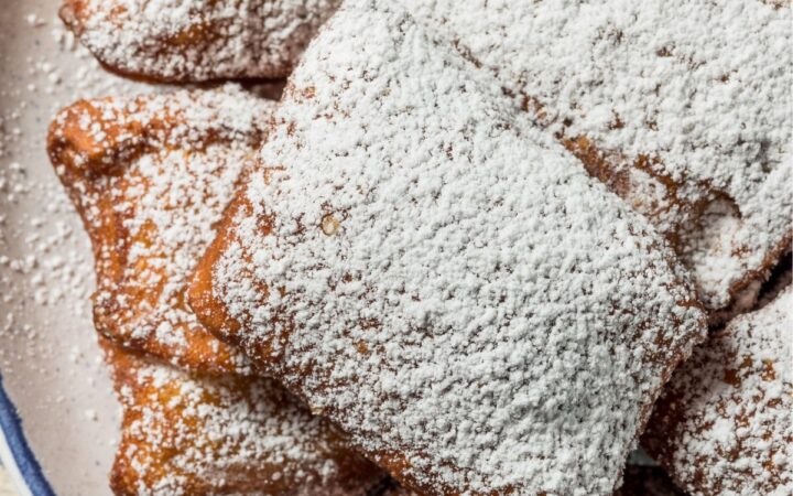 Overhead image of beignets dusted with powdered sugar on a plate