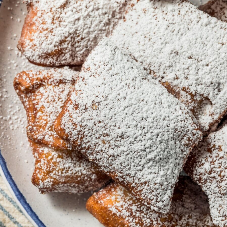 Overhead image of beignets dusted with powdered sugar on a plate