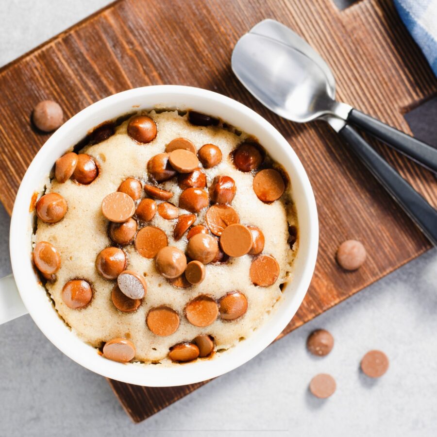 Overhead image of a chocolate chip mug cake on a wooden cutting board