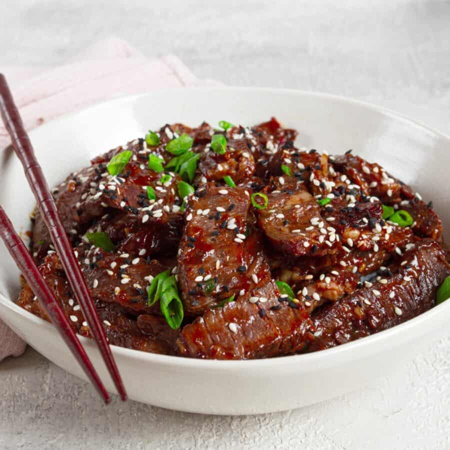 Close up image of Crispy Beef in a white bowl with chopsticks