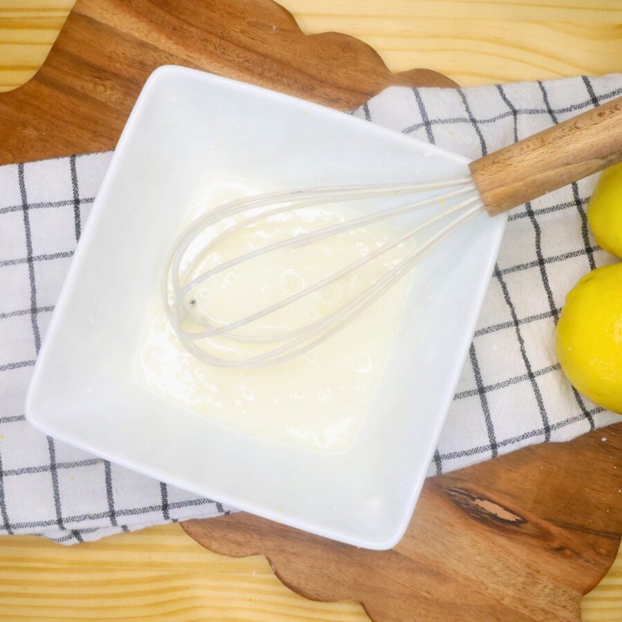 Lemon glaze for brownies in a bowl with a whisk