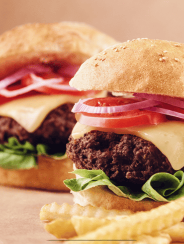 Close up image of oven baked burgers and fries on parchment paper